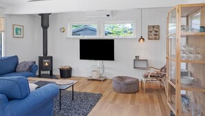 A living room with a fireplace, a sofa, a television, and a glass cabinet. - Stunning home in Væggerløse with WiFi (Væggerløse)