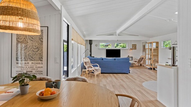 A spacious living area with a blue sofa, wooden dining table with fruit, and a hanging light fixture. - Stunning home in Væggerløse with WiFi (Væggerløse)