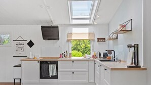 A modern kitchen with a skylight, a window with a view of greenery, white cabinetry, and a wooden countertop. - Stunning home in Væggerløse with WiFi (Væggerløse)