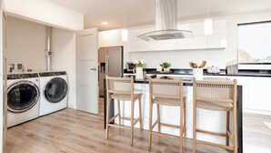 Una cocina moderna con lavadora y secadora integradas, taburetes de bar de madera y un ventanal con vistas.