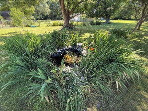 Un jardín con un estanque, rodeado de diversas plantas y árboles.