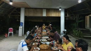 A group of people seated around a long table outdoors, eating various dishes. - Monte Carlo Camiguin Ruins, Looc Catarman Camiguin (Catarman)