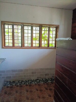 Ein Zimmer mit Fenster, Fliesenboden und einer Holzwand.