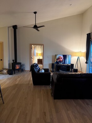 Un salon équipé d’une télévision, d’une cheminée et d’un ventilateur de plafond.