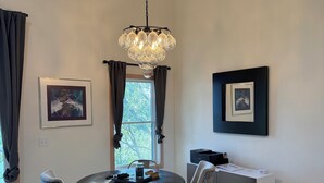 Uma área de refeições com uma mesa redonda, cadeiras, um candelabro e obras de arte nas paredes.