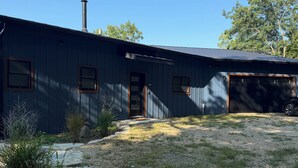 Um edifício térreo com garagem, chaminé e entrada com calçamento de brita.