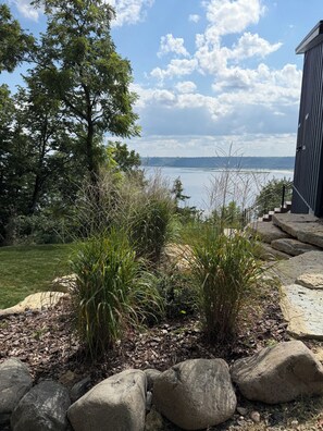 Un jardin aménagé offrant une vue sur une étendue d’eau et un bâtiment.