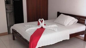 Een hotelkamer met een bed, een kledingkast en een zichtbare badkamer door een geopende deur.