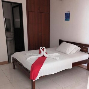 Une chambre d’hôtel avec un lit, une armoire et une salle de bain visible à travers une porte ouverte.