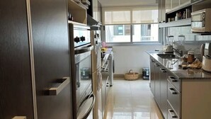 A modern kitchen with stainless steel appliances, a central island, and a view to the outside.