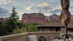 Una terraza con asientos al aire libre, vistas a formaciones rocosas rojas y un cielo despejado.