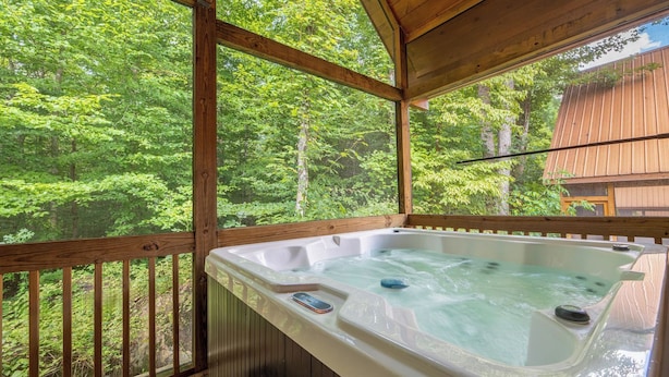 A hot tub in a wooden cabin with a view of a forest. - Dancing Bear Hideaway - Hot Tub, Resort Pool & Wooded Mountain Retreat (Gatlinburg)