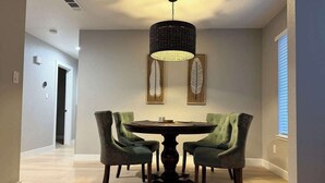 A dining area with a round table and four chairs, a hanging light fixture, and two wall-mounted feather art pieces. - Modern Blue Marina 2 bed 2 bath garage whole home (Modesto)