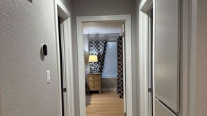 A hallway with a wooden floor, a door on the right, and a light fixture on the ceiling. - Modern Blue Marina 2 bed 2 bath garage whole home (Modesto)