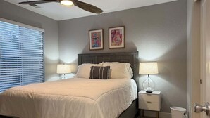 A bedroom with a bed, two bedside lamps, a ceiling fan, a nightstand, and a window with blinds. - Modern Blue Marina 2 bed 2 bath garage whole home (Modesto)