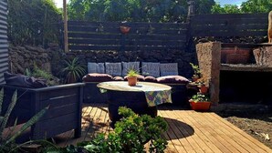 A patio with a wooden table, seating, and potted plants. - Te Maori House (Hanga Roa)