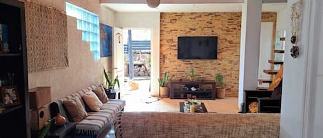A living room with a sofa, a TV mounted on a brick wall, and a fireplace.
