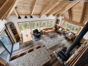 A spacious loft-style living area with a high ceiling, large windows, and a fireplace. - Spectacular views from cabin in Cle Elum. Hiking, fishing, ATVs, and breweries! (Cle Elum)