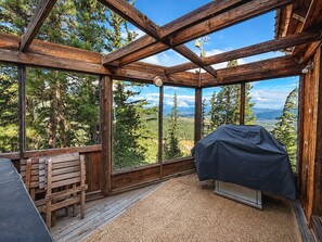 A wooden cabin with a large window offering a view of a forest and mountains. - Spectacular views from cabin in Cle Elum. Hiking, fishing, ATVs, and breweries! (Cle Elum)