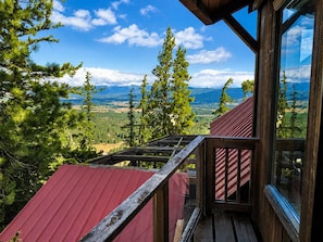 A wooden cabin with a red roof, large windows, and a view of a mountainous landscape. - Spectacular views from cabin in Cle Elum. Hiking, fishing, ATVs, and breweries! (Cle Elum)