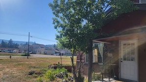 Een huis met een veranda en een garage. Voor het huis staat een boom.