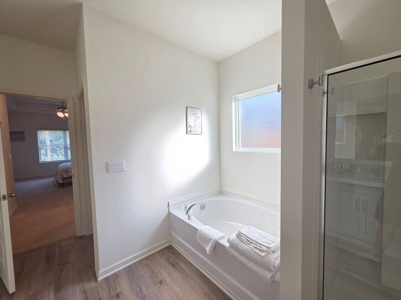 Un baño con bañera, ducha y zona de ducha con mampara de vidrio.