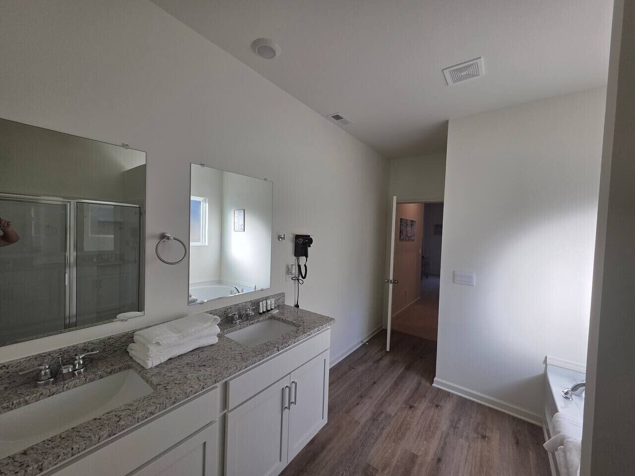 A modern bathroom with a double sink, a large mirror, and a walk-in shower.