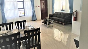 Una sala de estar con sofá, una mesa de comedor con sillas, una mesa de centro y un ventilador de techo.