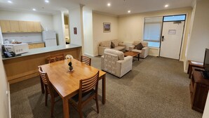 Een knus woongedeelte met een kitchenette, een eethoek en een zithoek met banken en een salontafel.