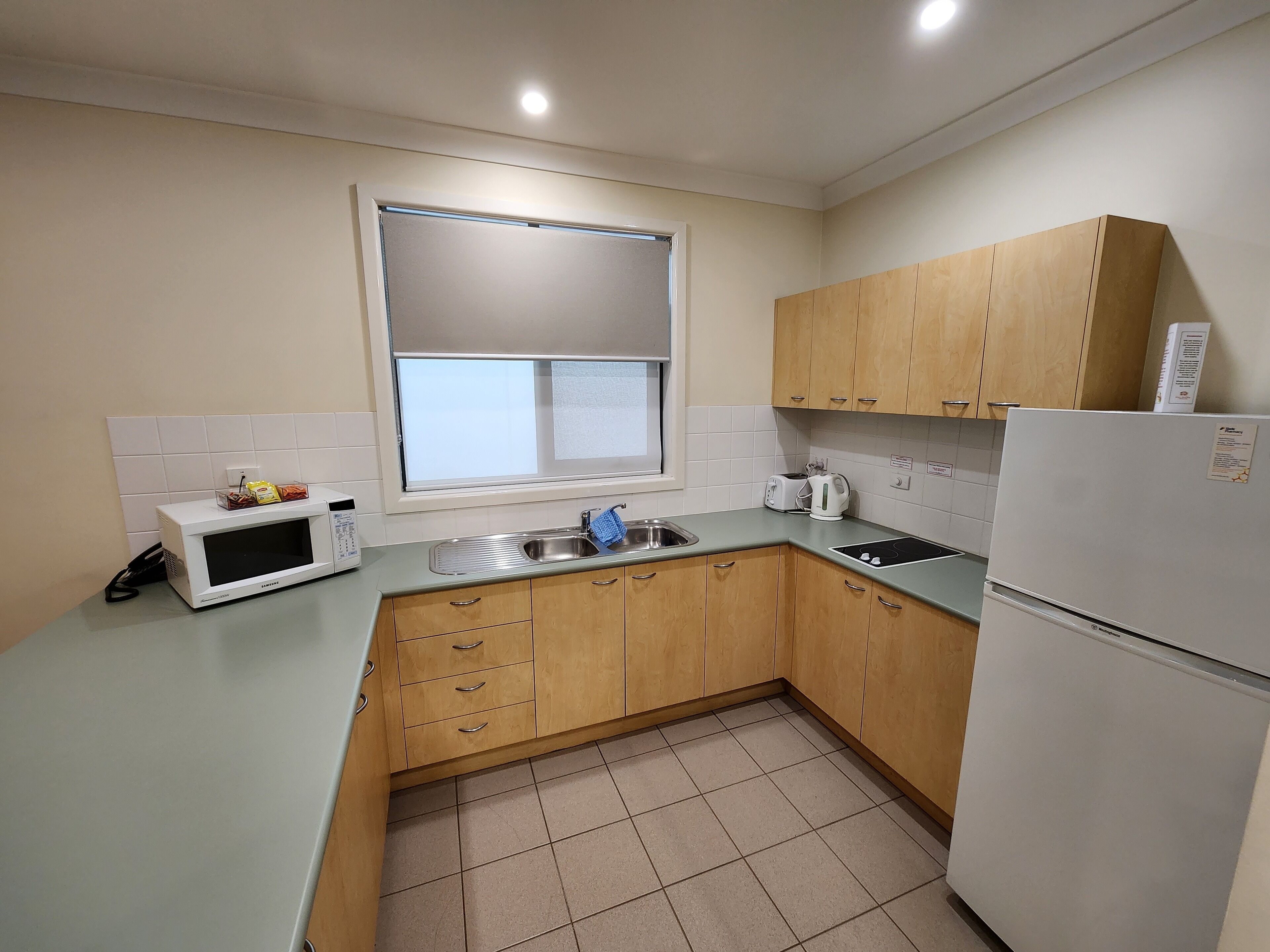 A compact kitchen with a microwave, toaster, sink, and a refrigerator.