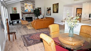 Ein geräumiges Wohnzimmer mit Kamin, einer großen Couch und einem Essbereich mit rundem Tisch und Stühlen.