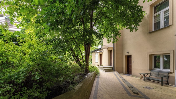 A paved pathway leading to a building with a bench and a small table. - Park Krakowski Comfy Studio (Kraków)