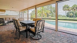 A covered patio with a pool view, outdoor seating, and a brick floor. - Golf Course Villa w/Pool & Yard, Near Wellington! (Wellington)