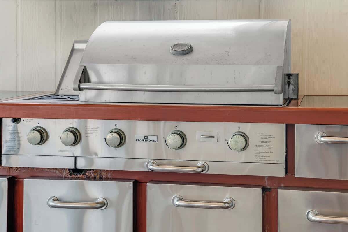 A stainless steel grill with a control panel and multiple storage drawers.