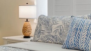 A bed with a patterned bedspread, a bedside lamp, and a window with blinds. - Golf Course Villa w/Pool & Yard, Near Wellington! (Wellington)
