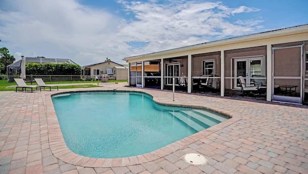 A swimming pool with a brick deck, lounge chairs, and a covered patio area. - Golf Course Villa w/Pool & Yard, Near Wellington! (Wellington)
