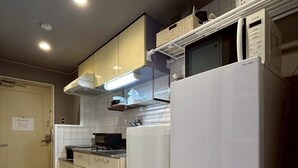 Una cocina moderna con armarios blancos, un refrigerador de acero inoxidable y un microondas encima.
