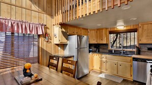 Una cocina con armarios de madera, un refrigerador de acero inoxidable, una ventana con vistas y un comedor con mesa y sillas.