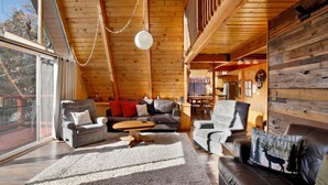 Interior acogedor de una cabaña de troncos con techo alto, chimenea y comedor.