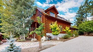 A log cabin with a stone foundation, a wooden deck, and a clear sky.