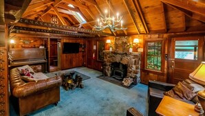Un acogedor interior de cabaña con chimenea de piedra, muebles de cuero y techo de madera abovedado.