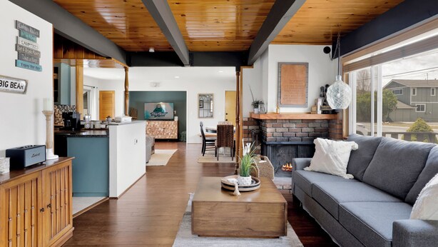 Un salón espacioso con techo de madera, un sofá gris, una mesa de centro y una chimenea.