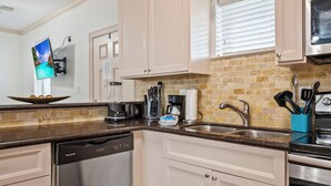 A kitchen with white cabinets, a dishwasher, a coffee maker, and a stove.
