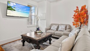 Una sala de estar con televisión, ventilador de techo, sofá y mesa de centro.
