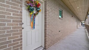 Un pasillo con una puerta blanca decorada con un colorido arreglo floral.