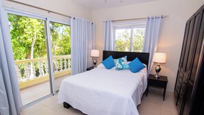 A bedroom with a large bed, two bedside tables, and a view of a balcony. - Lodging Villa 766 in Sosua (Sosúa)
