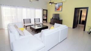 A living room with a white sofa, a glass coffee table, and two chairs. There are ceiling fans and a chandelier. - Lodging Villa 766 in Sosua (Sosúa)