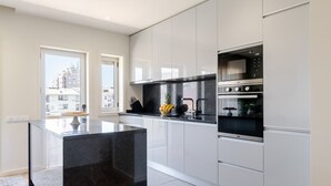 Een moderne keuken met een centraal eiland, roestvrijstalen apparatuur en witte kastjes.