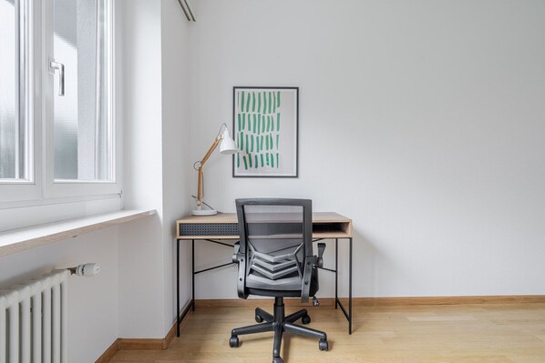 A modern office space with a desk, chair, and a framed abstract artwork on the wall.