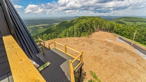 A wooden deck with a view of a forested landscape.